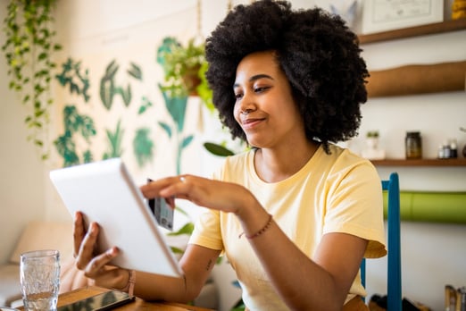 A smiling young woman checking her BMO Performance chequing account balance on her tablet.