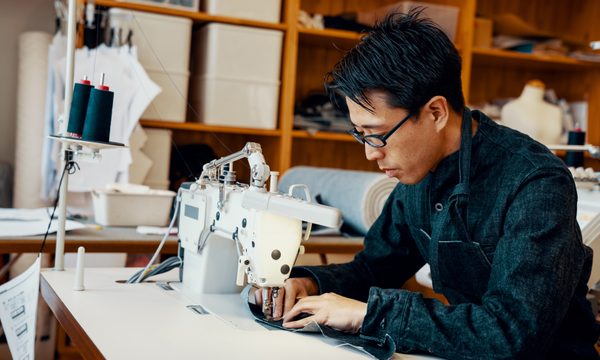 Man with glasses sits at a sewing machine