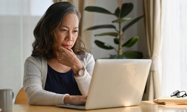 Woman looking at laptop contemplative.
