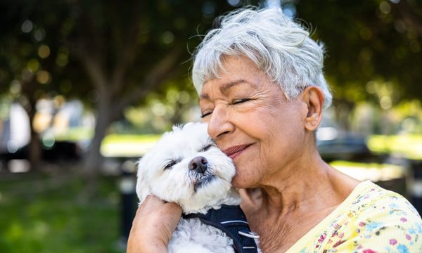 older woman cuddling small white dog