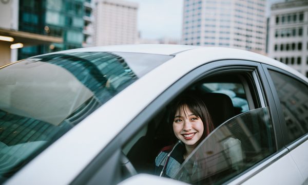 woman looking out window of car in city