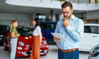 Person looking at tablet at car dealership