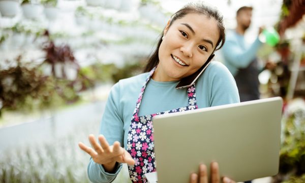 Asian Woman Working at the Plants Nursery Using Smartphone and Laptop