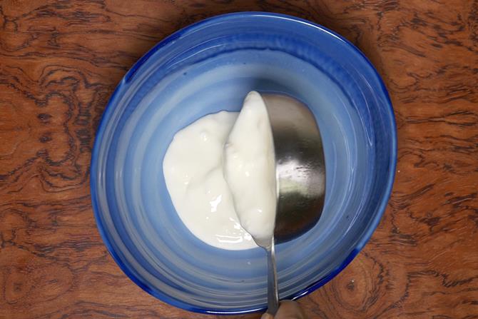 add curd to a bowl to make eggless sponge cake