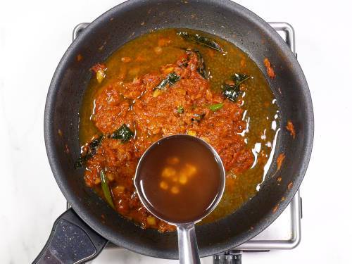 pouring tamarind water to make coconut salmon curry