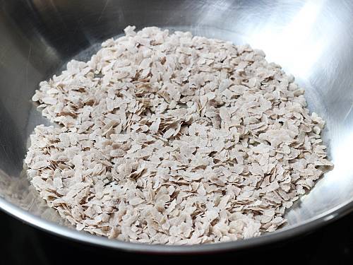 roasting brown poha in a pan to make chivda